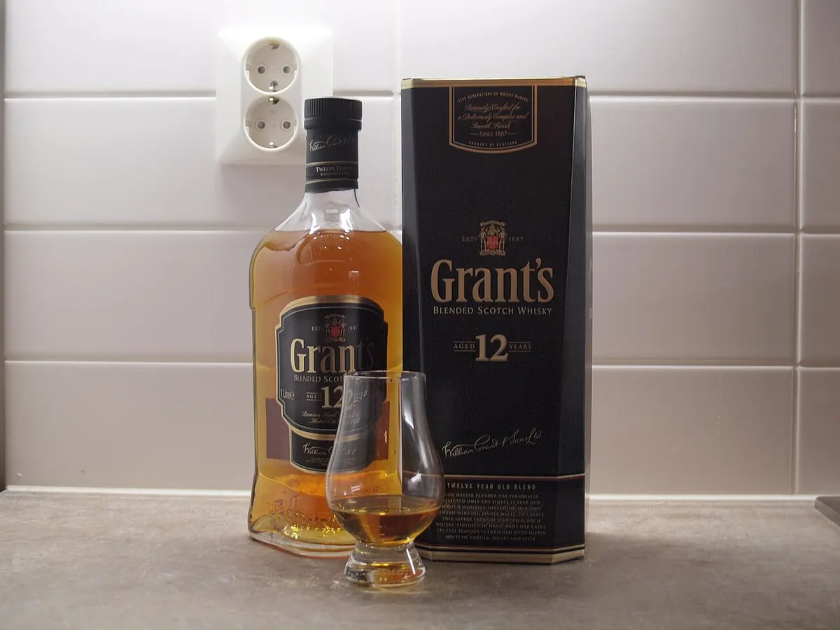 A Glencairn whisky glass poured next to a bottle of blended scotch