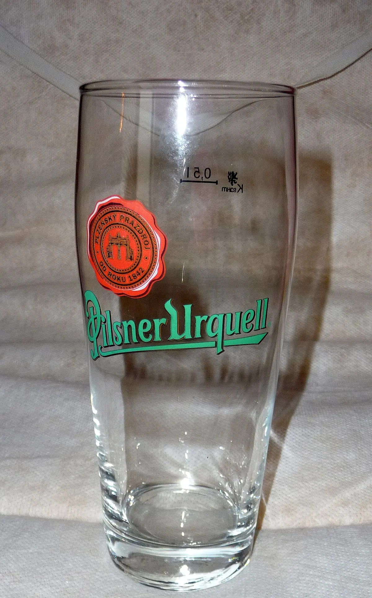 A cold beer poured into a pilsner glass with a thick head of foam